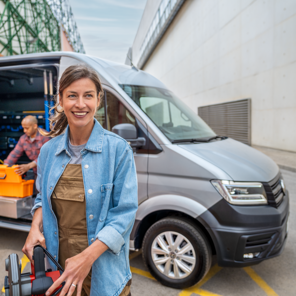 Eine Frau vor einem silbernen Crafter Kastenwagen, ein Mann kniet auf der Ladefläche.