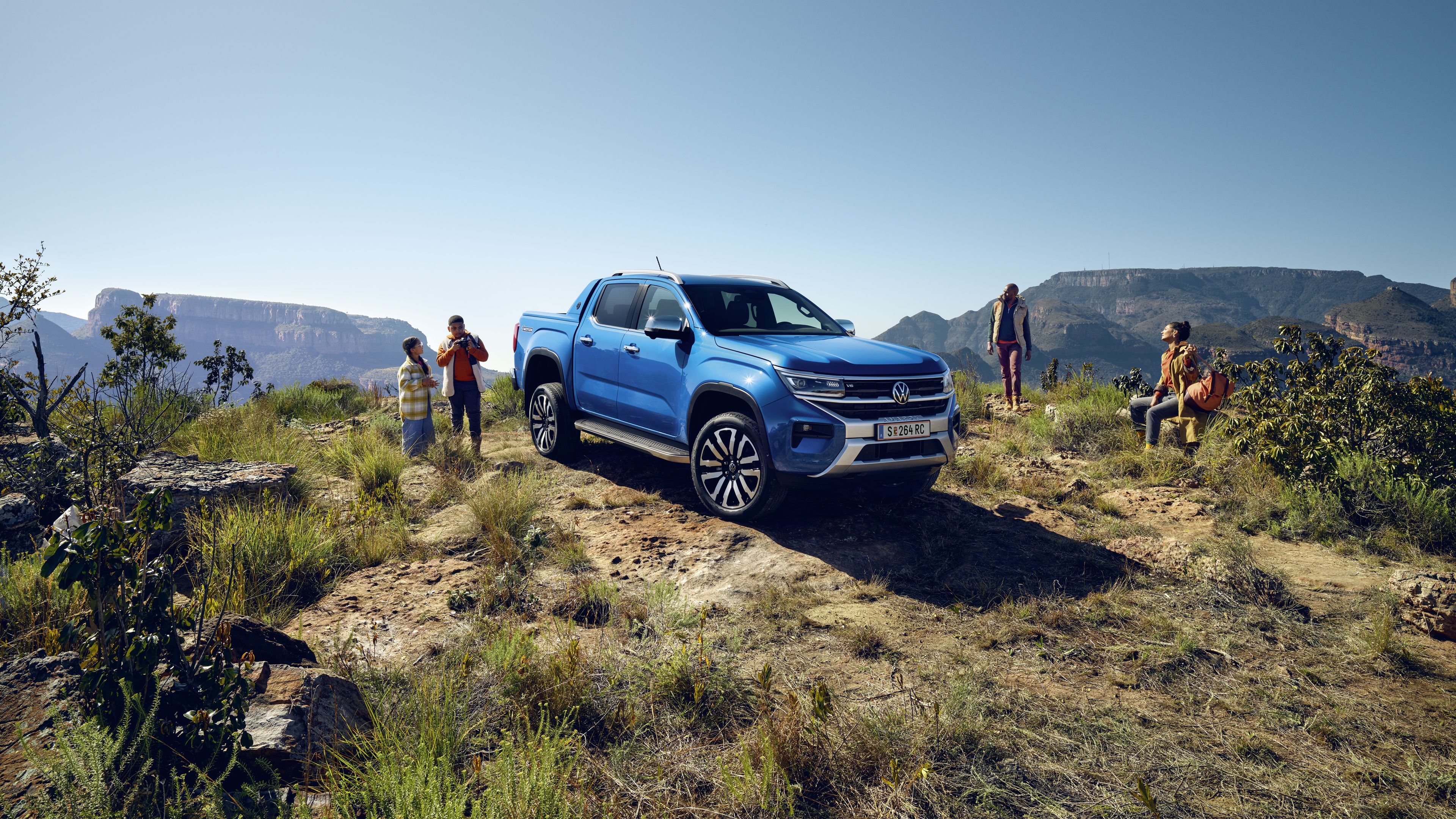 Der neue VW Amarok steht im Gelände neben einer Familie