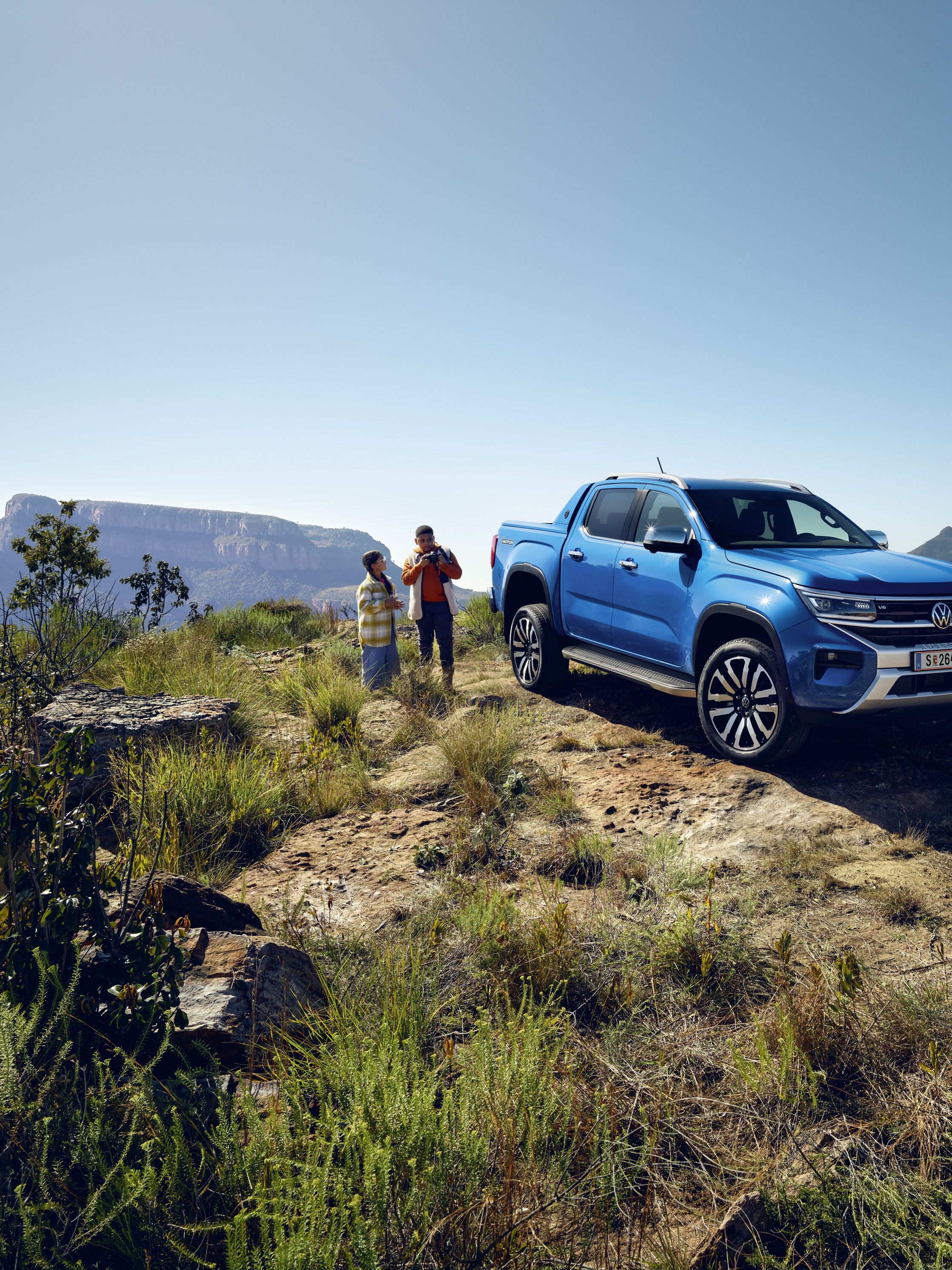 Der neue VW Amarok steht im Gelände neben einer Familie