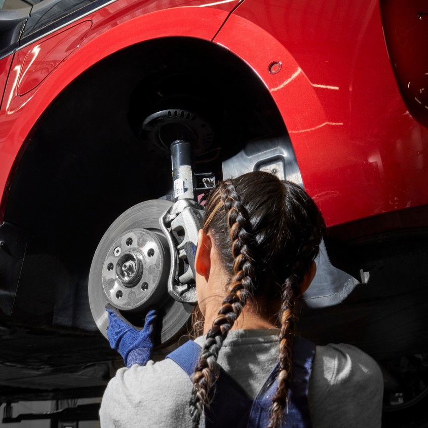 Eine VW Mechanikerin wechselt die Bremsscheiben bei einem VW Nutzfahrzeug