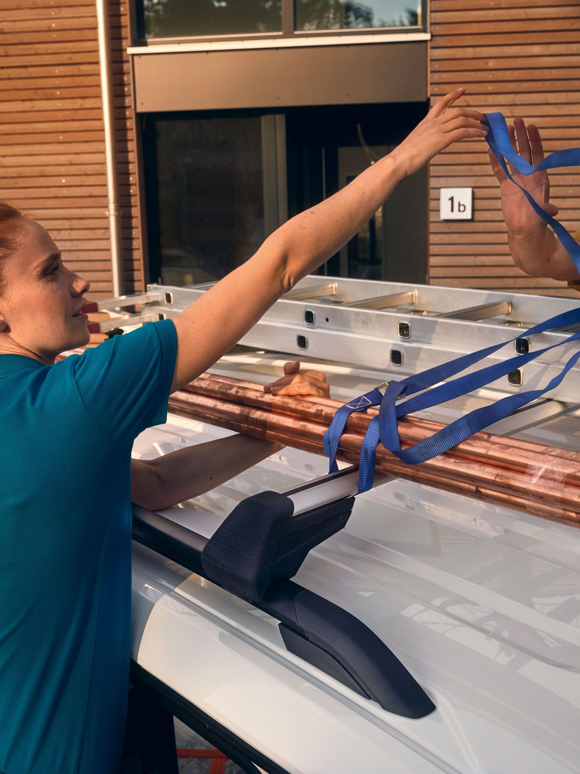 Ein Handwerker-Team fixiert eine Leiter auf der Dachreling eines VW Caddy Cargo.