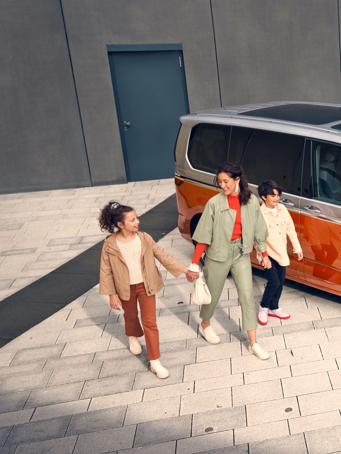 Eine Familie läuft vergnügt neben dem stehenden VW Multivan Energetic T7 2021 her