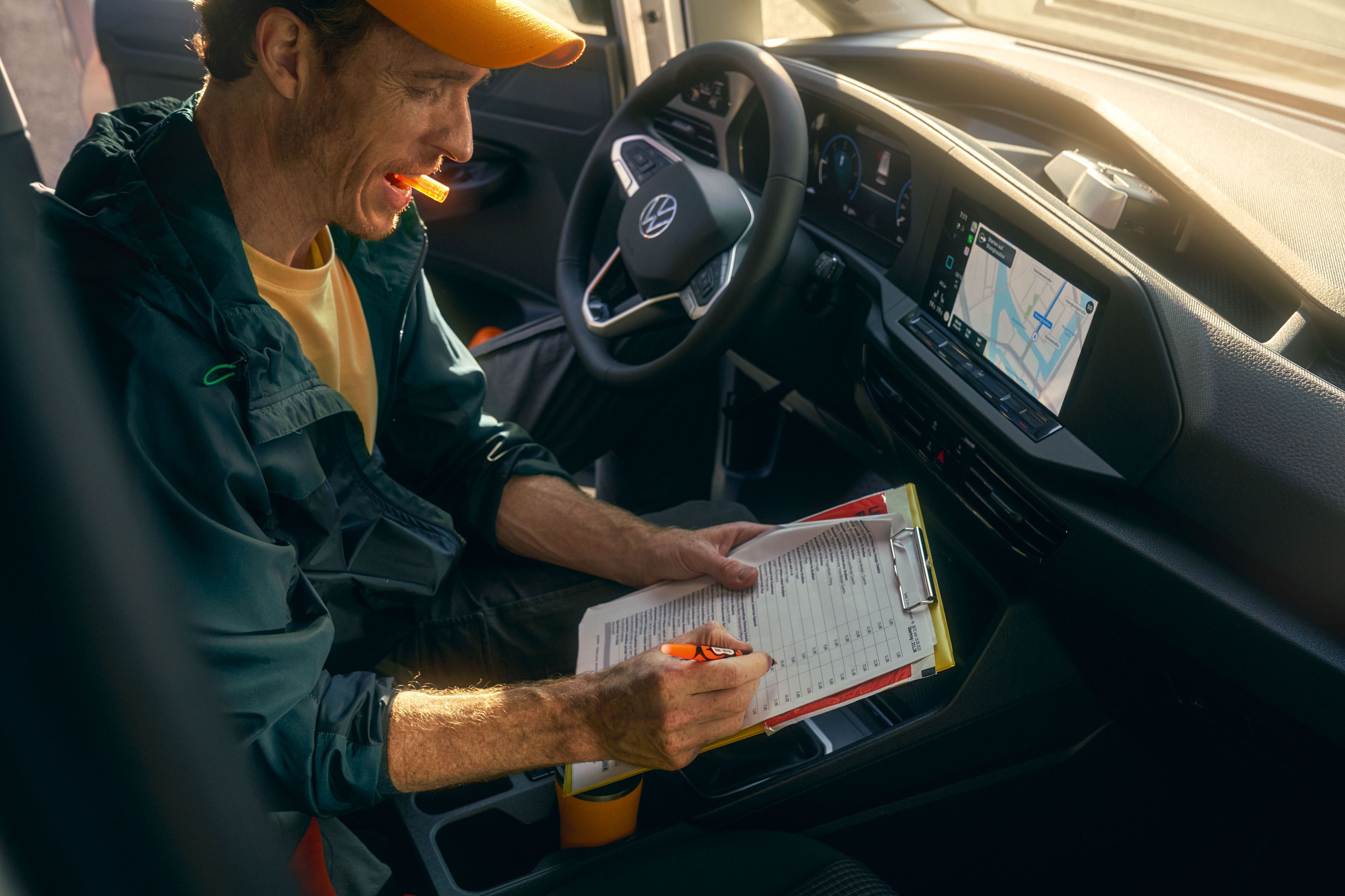 Ein Mann sitzt in einem VW Caddy Cargo und schreibt auf einem Klemmbrett.