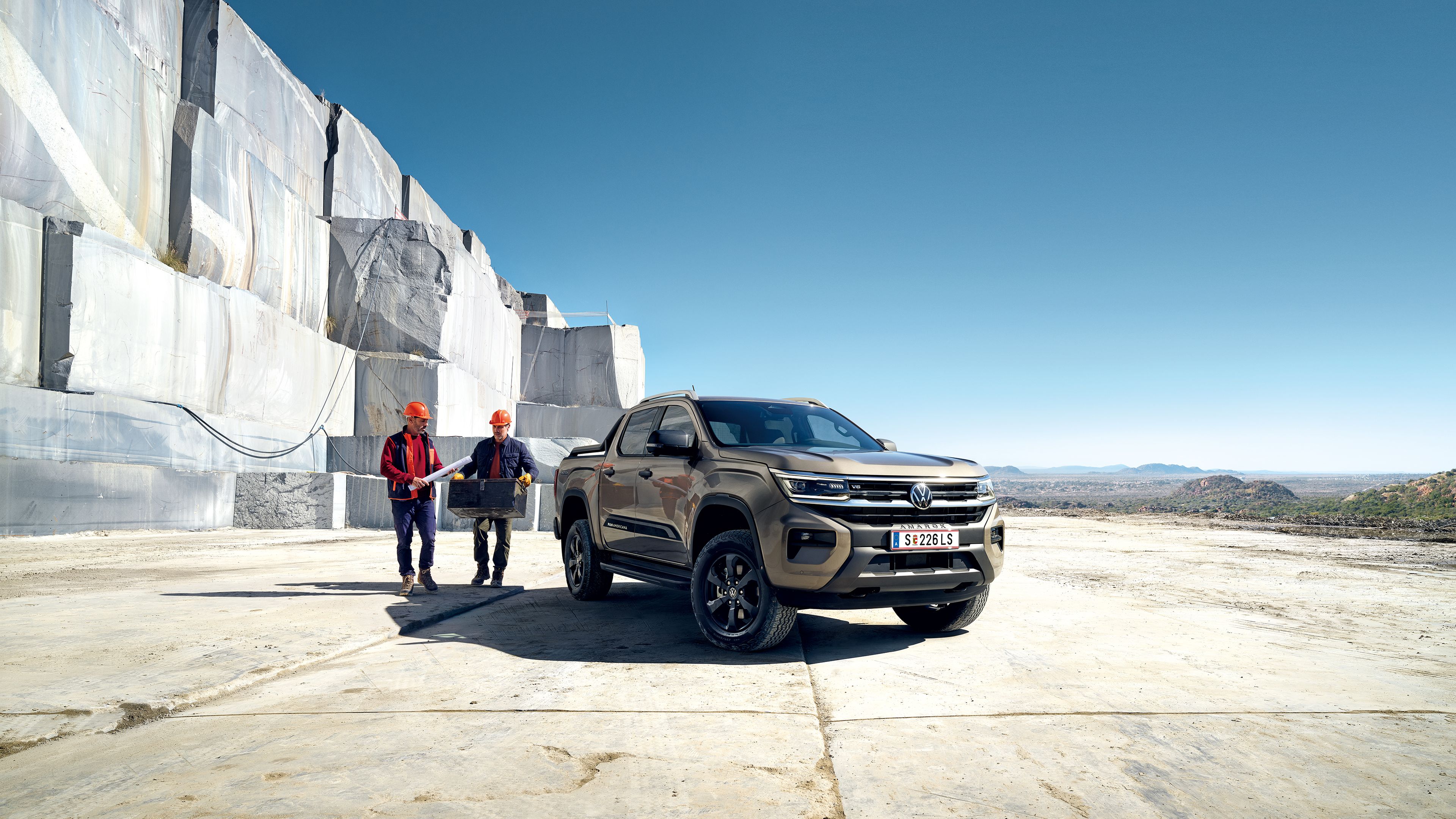 Zwei Arbeiter stehen neben dem neuen VW Amarok