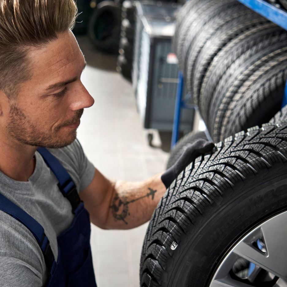 Ein Volkswagen Service Techniker nimmt einen Reifen aus einem Lagerregal