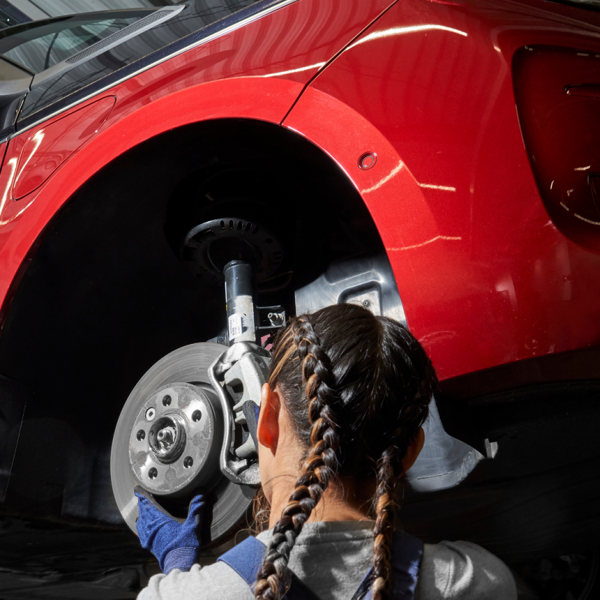 Eine VW Mechanikerin wechselt die Bremsscheiben bei einem VW Nutzfahrzeug