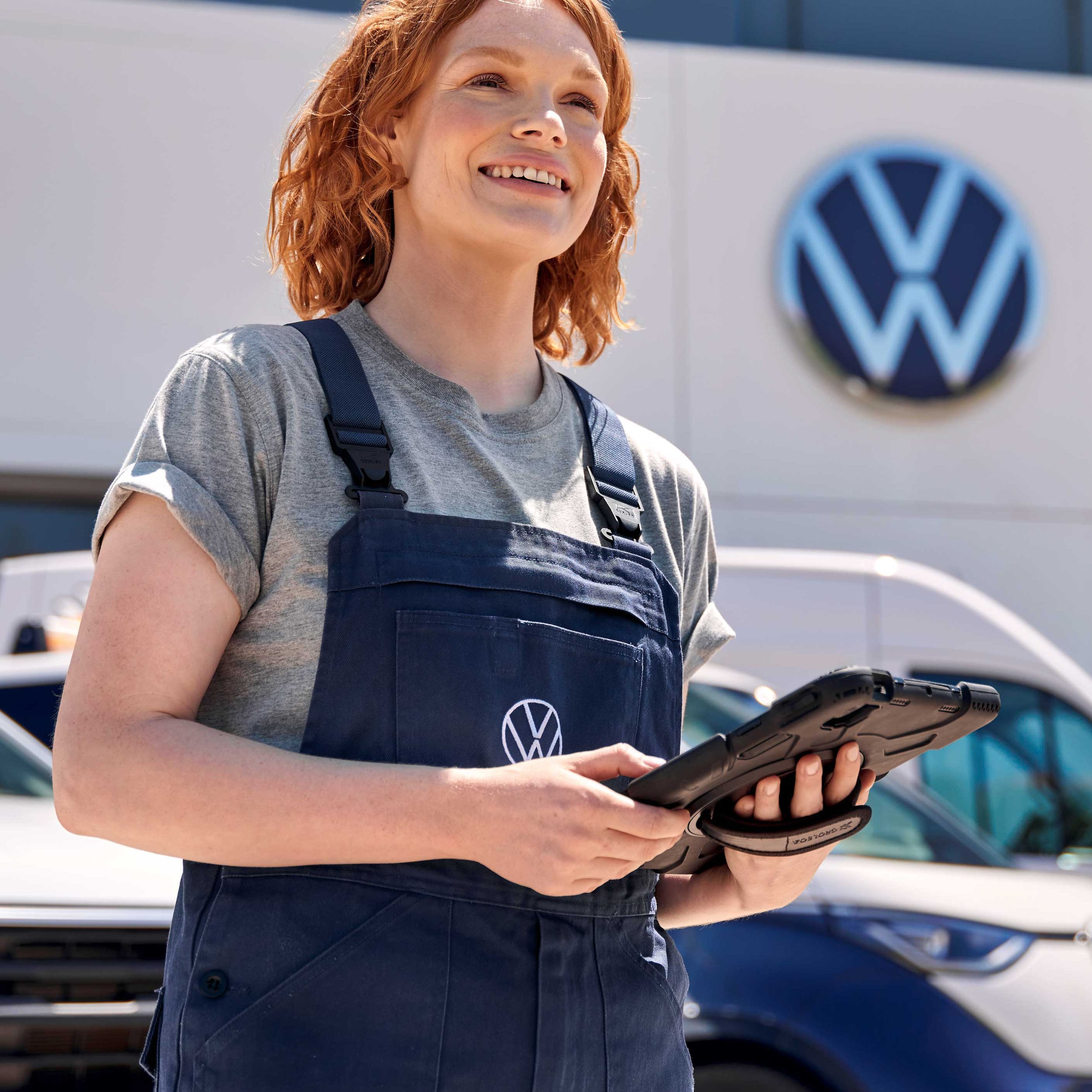 Eine Volkswagen Service Mitarbeiterin vor einem Volkswagen Service Gebäude
