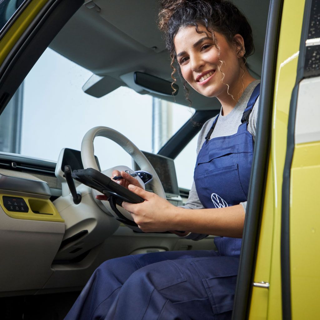 VW Service-Mitarbeiterin im Führerhaus eines VW-Nutzfahrzeuges