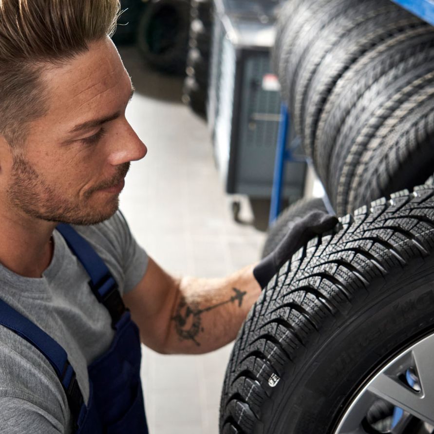 Ein Volkswagen Service Techniker nimmt einen Reifen aus einem Lagerregal