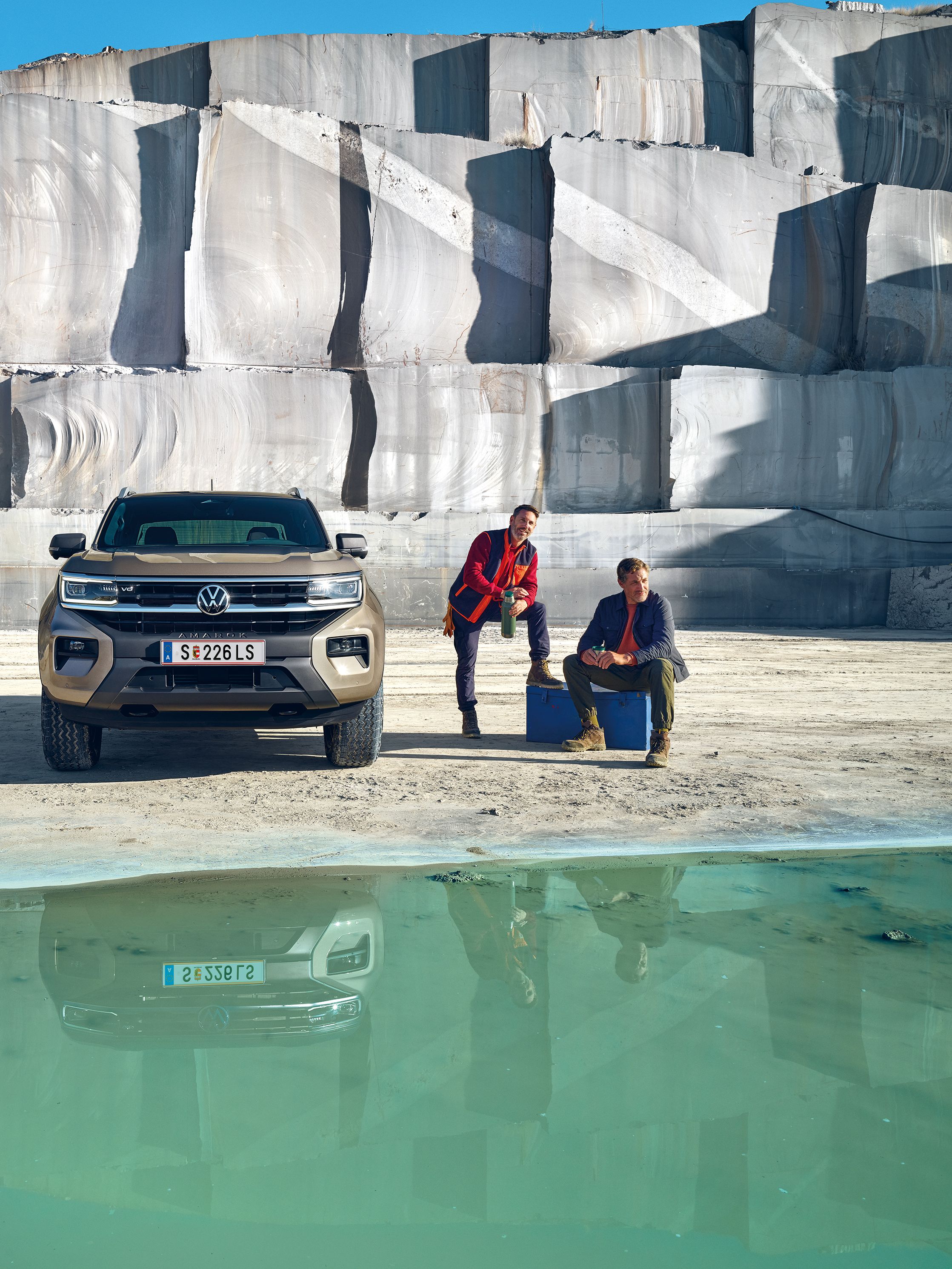 Der neue VW Amarok steht im Freien neben zwei Männern