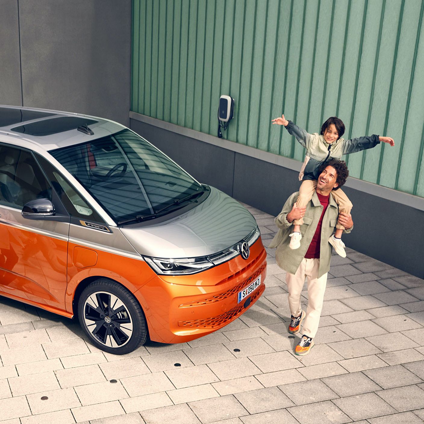 Eine Familie läuft vergnügt neben dem stehenden VW Multivan Energetic T7 2021 her