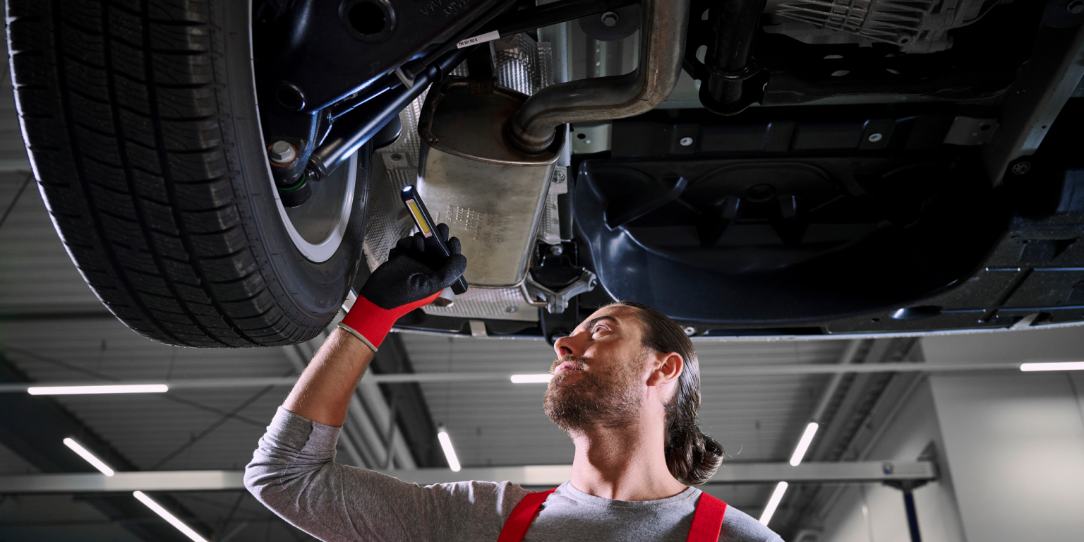 Ein VW Mechaniker bei der Kontrolle der Stoßdämpfer von einem VW Nutzfahrzeug