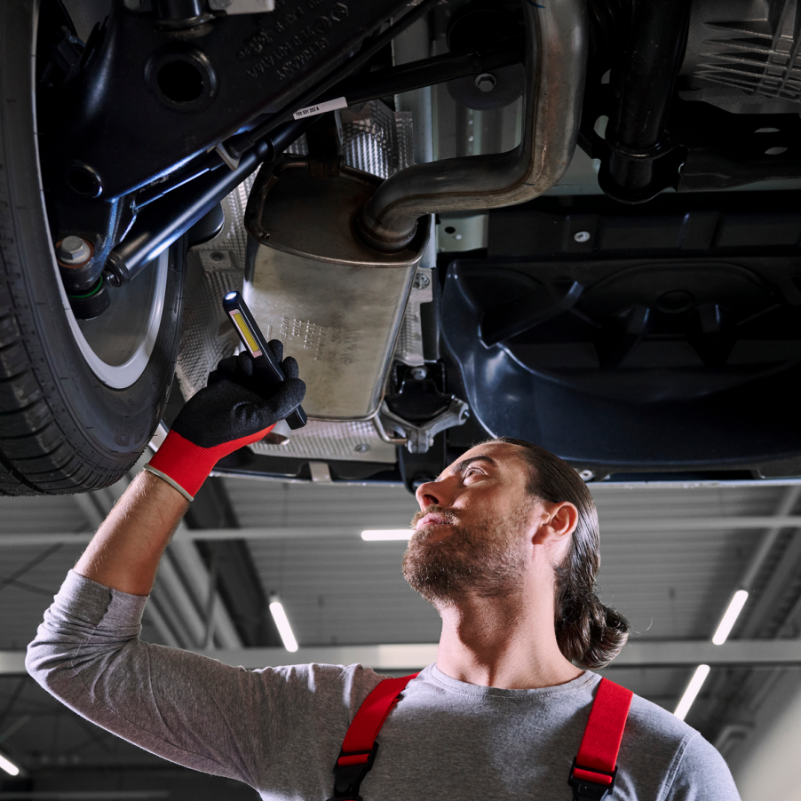 Ein VW Mechaniker bei der Kontrolle der Stoßdämpfer von einem VW Nutzfahrzeug